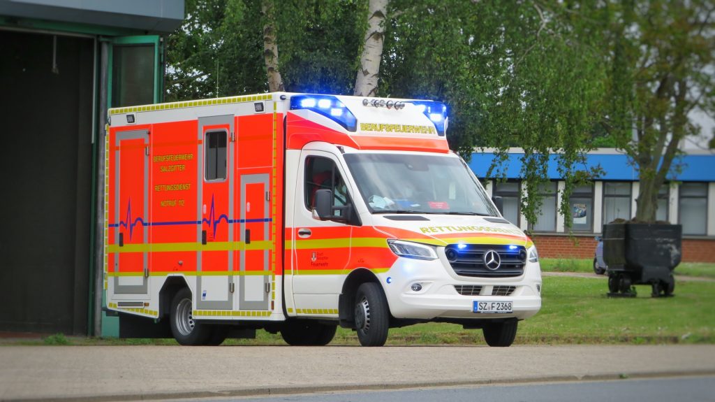 white and red ambulance parked on gray pavement